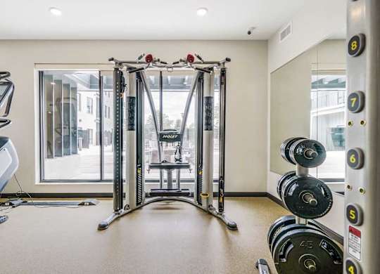 a 24-hour fitness center with a Smith machine and racks of weights