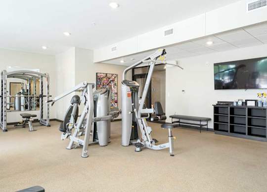a 24-hour fitness center with several weight machines and a tv