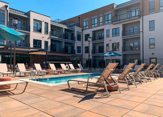a lounge pool with several chaise lounge chairs and umbrellas surrounding it