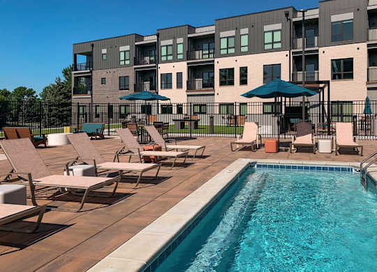 a lounge pool with several chaise lounge chairs and umbrellas surrounding it