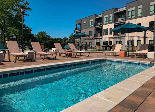 a lounge pool with several chaise lounge chairs and umbrellas surrounding it