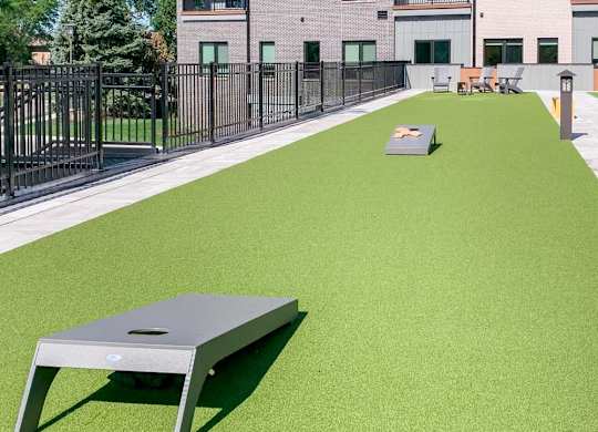 a turf green space with a set of cornhole boards