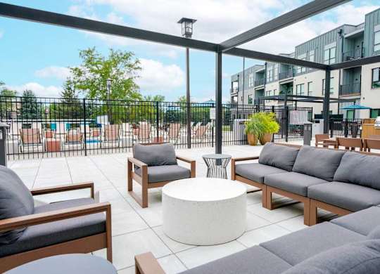 A courtyard patio with lounge seating and a pergola frame.