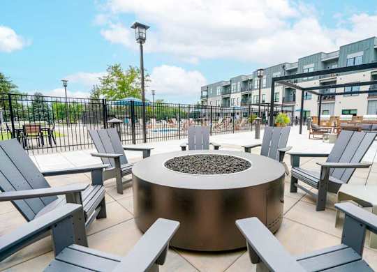 A conversational fire pit with several Adirondack chairs surrounding it.