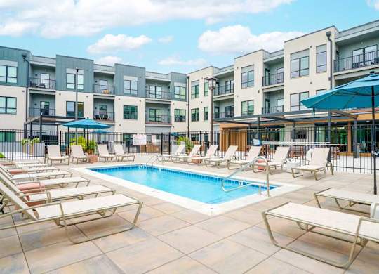 A lounge pool surrounded by several lounge chairs and umbrellas for shade.