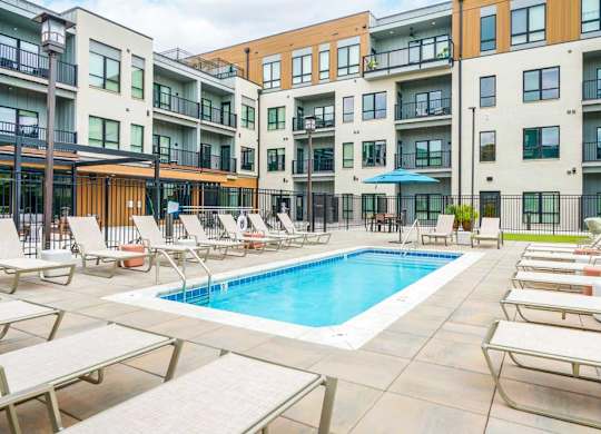 A lounge pool surrounded by several lounge chairs and umbrellas for shade.