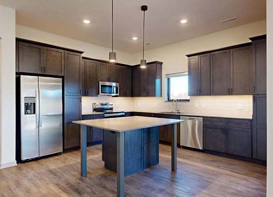 A modern kitchen with dark wood cabinets and stainless steel appliances.