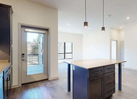 A kitchen with a large island and a view of a backyard.