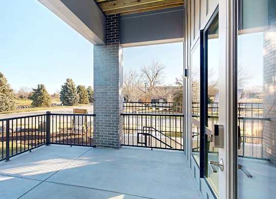 A balcony with a black railing and a view of trees and houses.