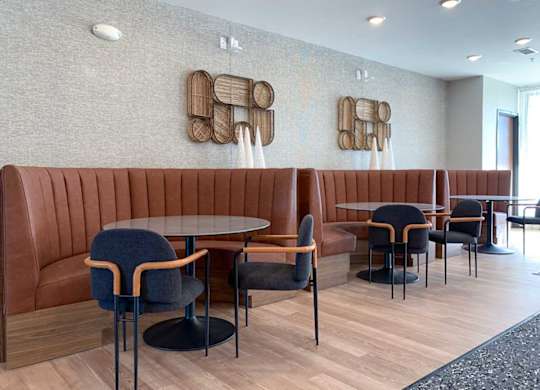 a modern dining/seating area with a brown leather booths and black chairs