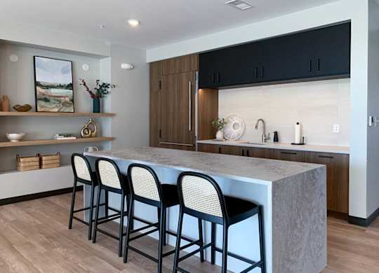 a kitchen with a marble island and black barstools