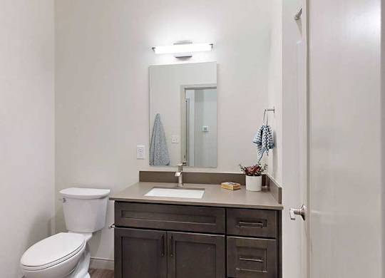 a bathroom with a quartz vanity sink and a mirror with overhead lighting