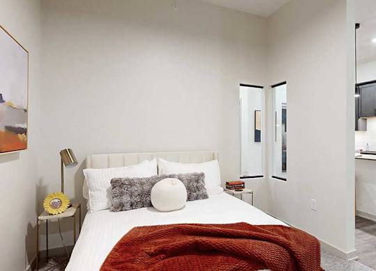 a bed with a red throw blanket and neutral-toned walls