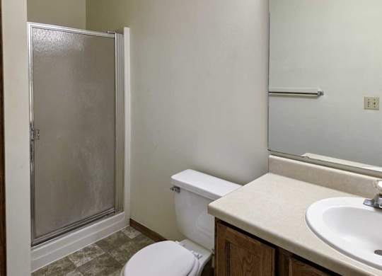 A bathroom with a sink, large mirror, and shower with a glass door.