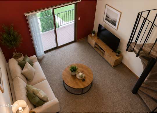 Two-story apartment living room with a loft layout, carpeted flooring, a spiral staircase, sliding glass door to a private balcony, and a cozy seating area with a TV console.