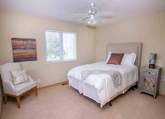 a bedroom with a white bed and a ceiling fan