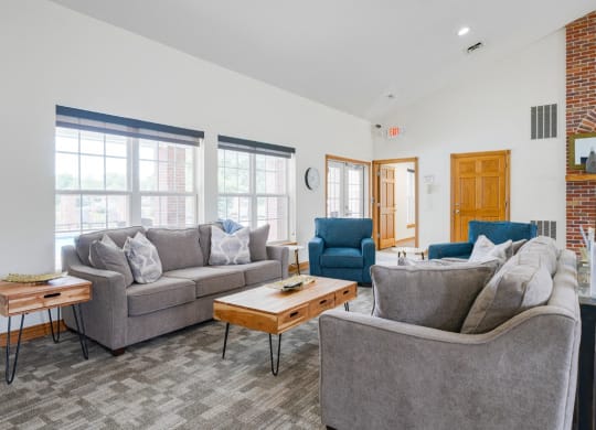 Lounging area in clubhouse with couches and chairs and a brick fireplace in the back