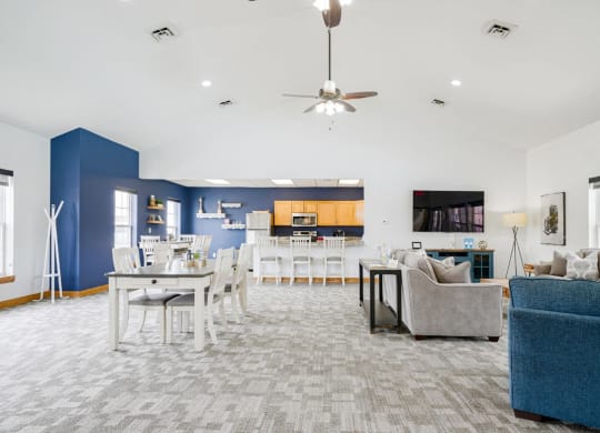 Community clubhouse with couches and a dining room with a table and chairs with the kitchen in the back
