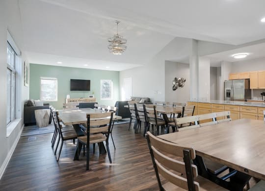 several tables and chairs next to a kitchen and a tv lounge space in the clubhouse