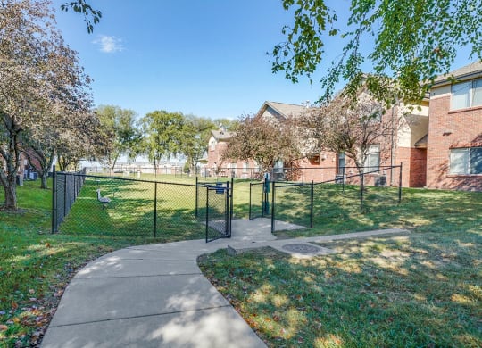 a fenced in dog park next to a sidewalk