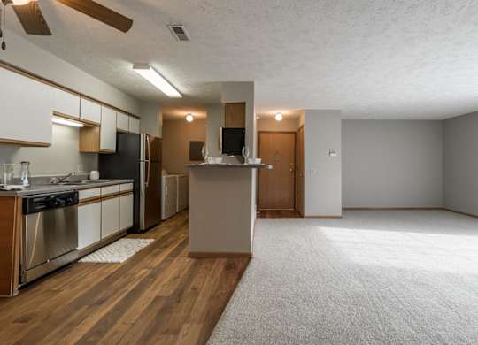 A kitchen with wooden floors that opens to living room