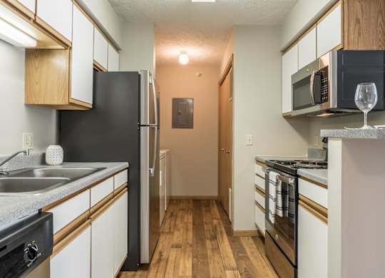 A kitchen with stainless steel appliances and white and oak cabinets.