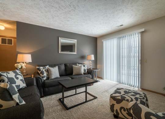 A living room with a grey couch, a coffee table, and a lamp.