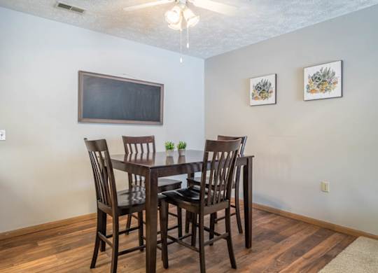 A dining room with a wooden table and chairs.