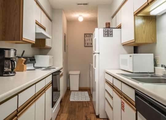 A kitchen with white appliances and white and oak cabinets.