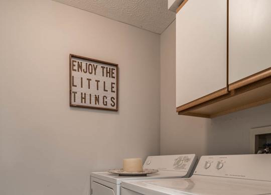 A laundry room with a washer and dryer and cabinet above them