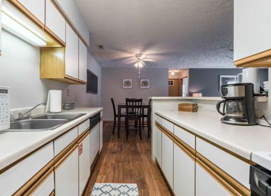 A kitchen with white cabinets and a wooden floor.