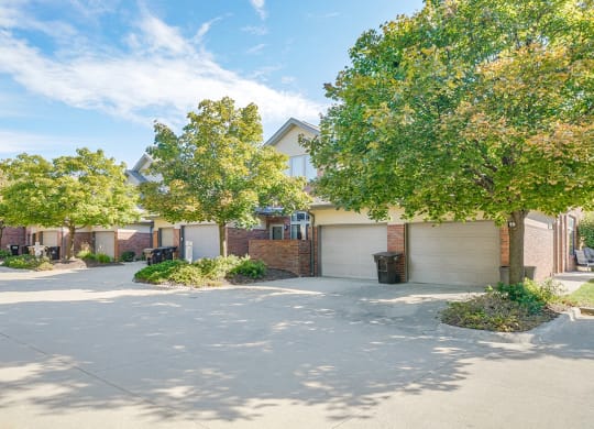 the exteriors of a row of villas with attached garages and trees lining the road
