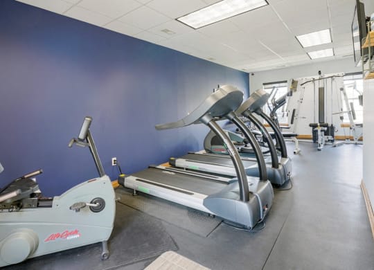 24-hour fitness center with a row of treadmills and other exercise equipment