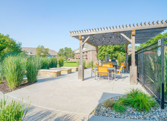 a patio with a pergola and a table and chairs next to a firepit