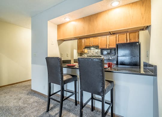 Renovated kitchen with dark counter tops and seating at the counter at Fountain Glen Apartments