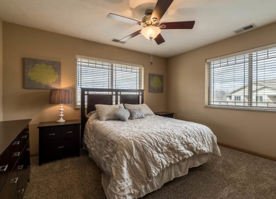 a bedroom with a queen bed, dark wood furniture, and a ceiling fan