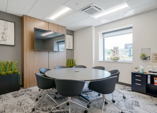 a conference room with a round table and chairs and a television