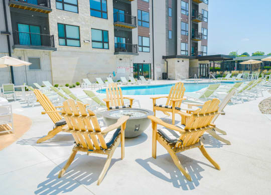 an outdoor pool with lounge chairs and a fire pit