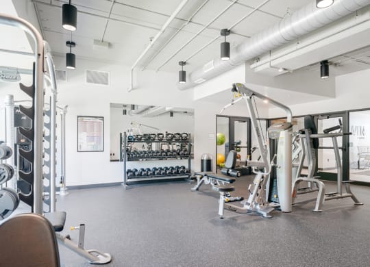 a gym with weights and other exercise equipment in a building with white walls