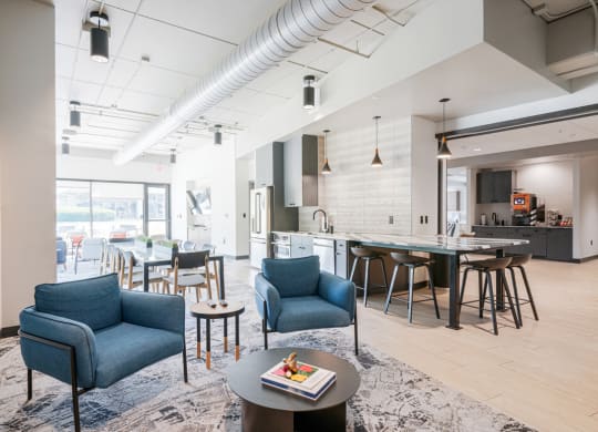 a living room with blue chairs and a kitchen with a table and chairs
