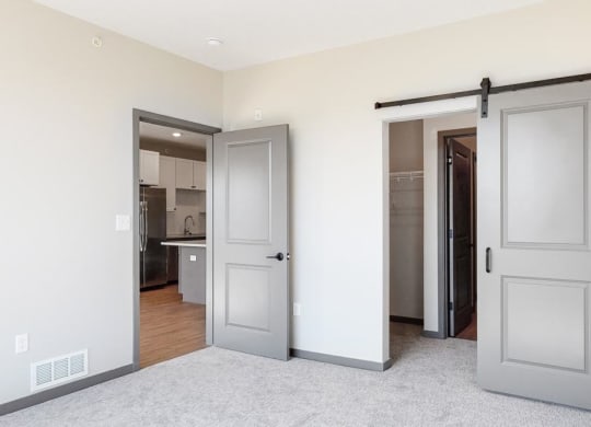 Sliding barn doors leading to closet space and the bathroom from the bedroom in the Bliss floor plan at Haven at Uptown in Lincoln, NE