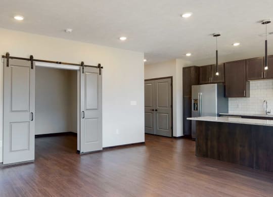 Living space with sliding barn doors leading to an office space in the Melody floor plan at Haven at Uptown in Lincoln, NE