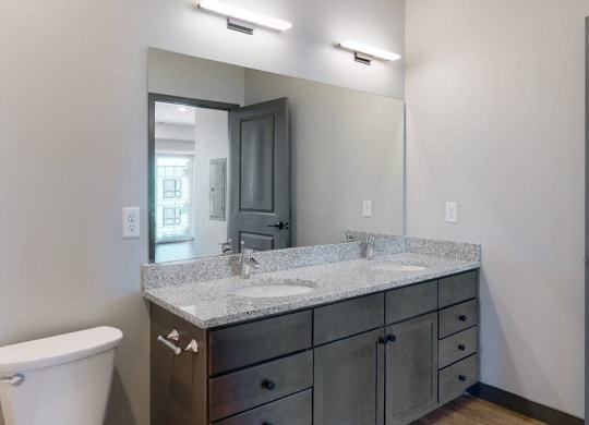 Dual sinks and light granite counter tops, as well is slate grey cabinetry for extra storage in the bathroom at Haven at Uptown in Linooln, NE