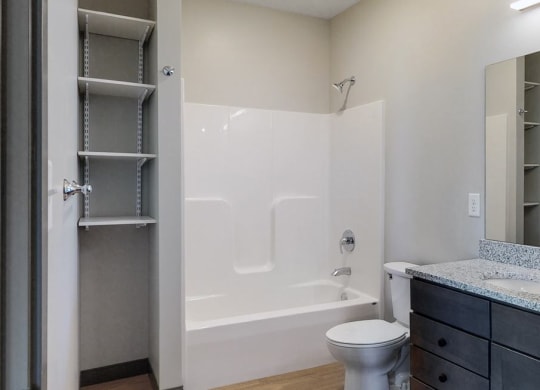 Bathroom with dual sink counter tops, a bathtub, and shelves for additional storage at Haven at Uptown in Lincoln, NE