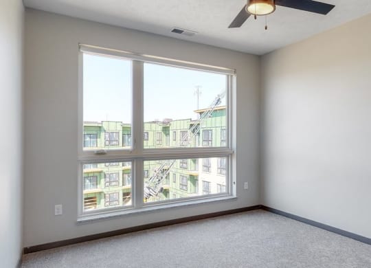 Bedroom with large window and ceiling fan in the Melody floor plan at Haven at Uptown in Lincoln, NE