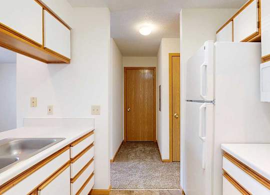 A galley kitchen with white appliances and wooden cabinets