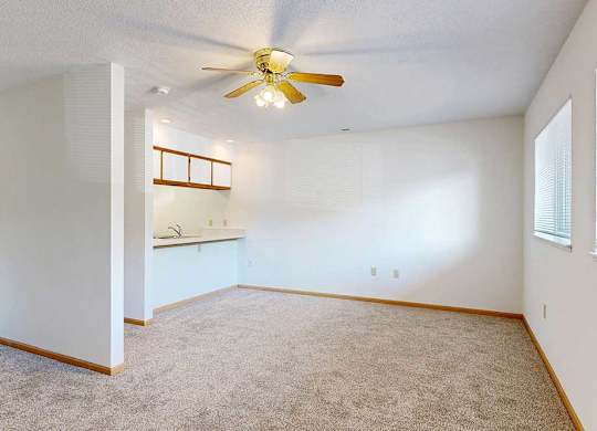 Open living space with carpet flooring and ceiling fan