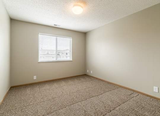 a bedroom with a carpeted floor and a window with blinds