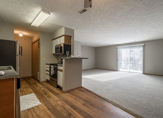 View of the kitchen with hardwood-style flooring and the living space with plenty of natural light at Eagle Run Apartments