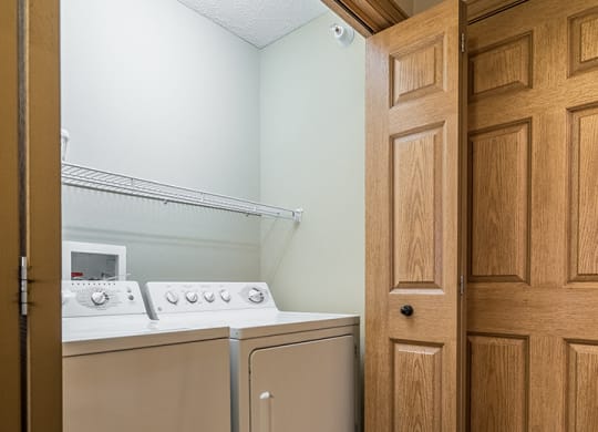 a full-sized washer and dryer with built-in overhead storage, in a hallway closet